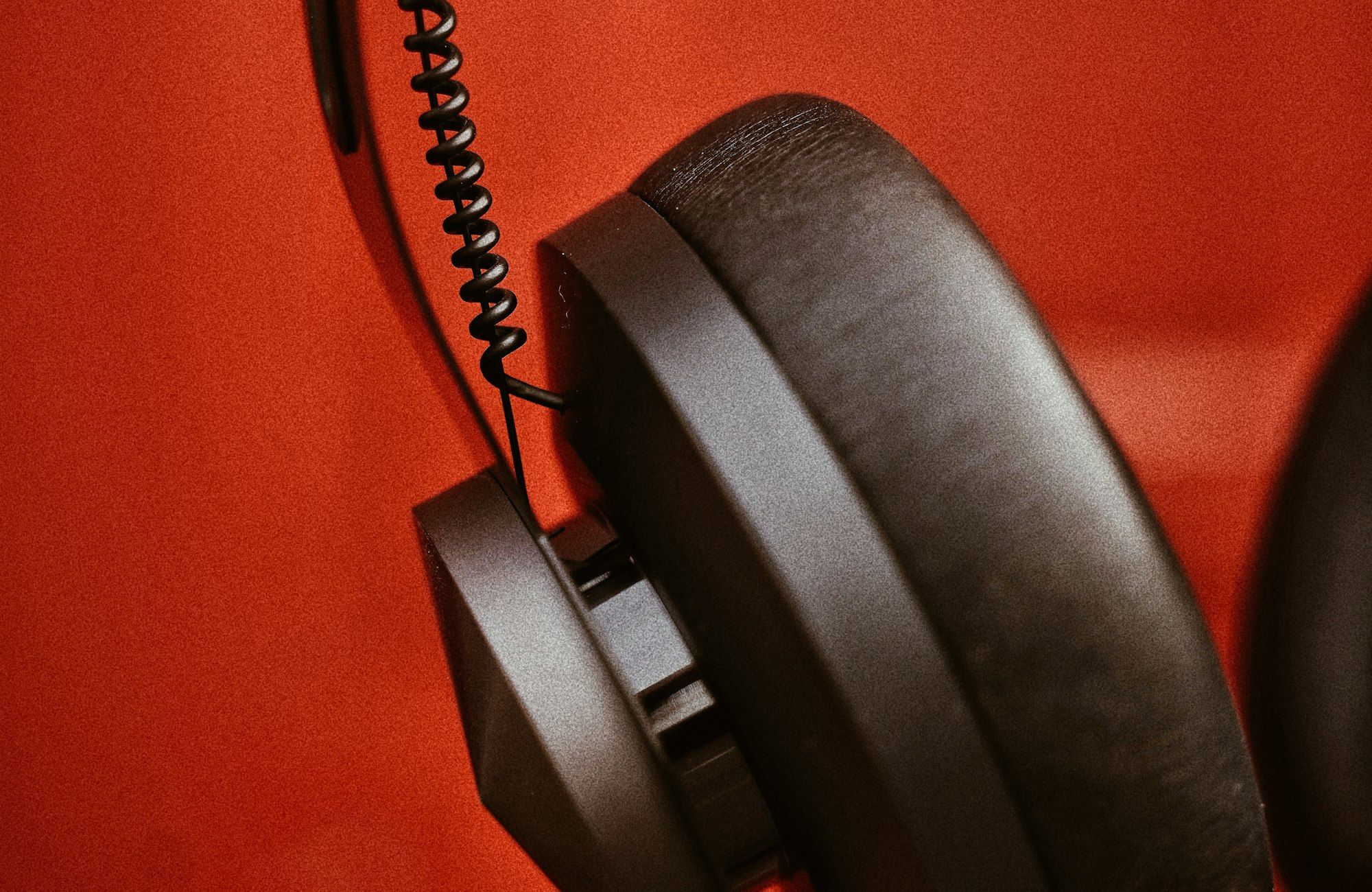 Brown leather HELM headphones against a deep red backdrop, warm macro detail of materials
