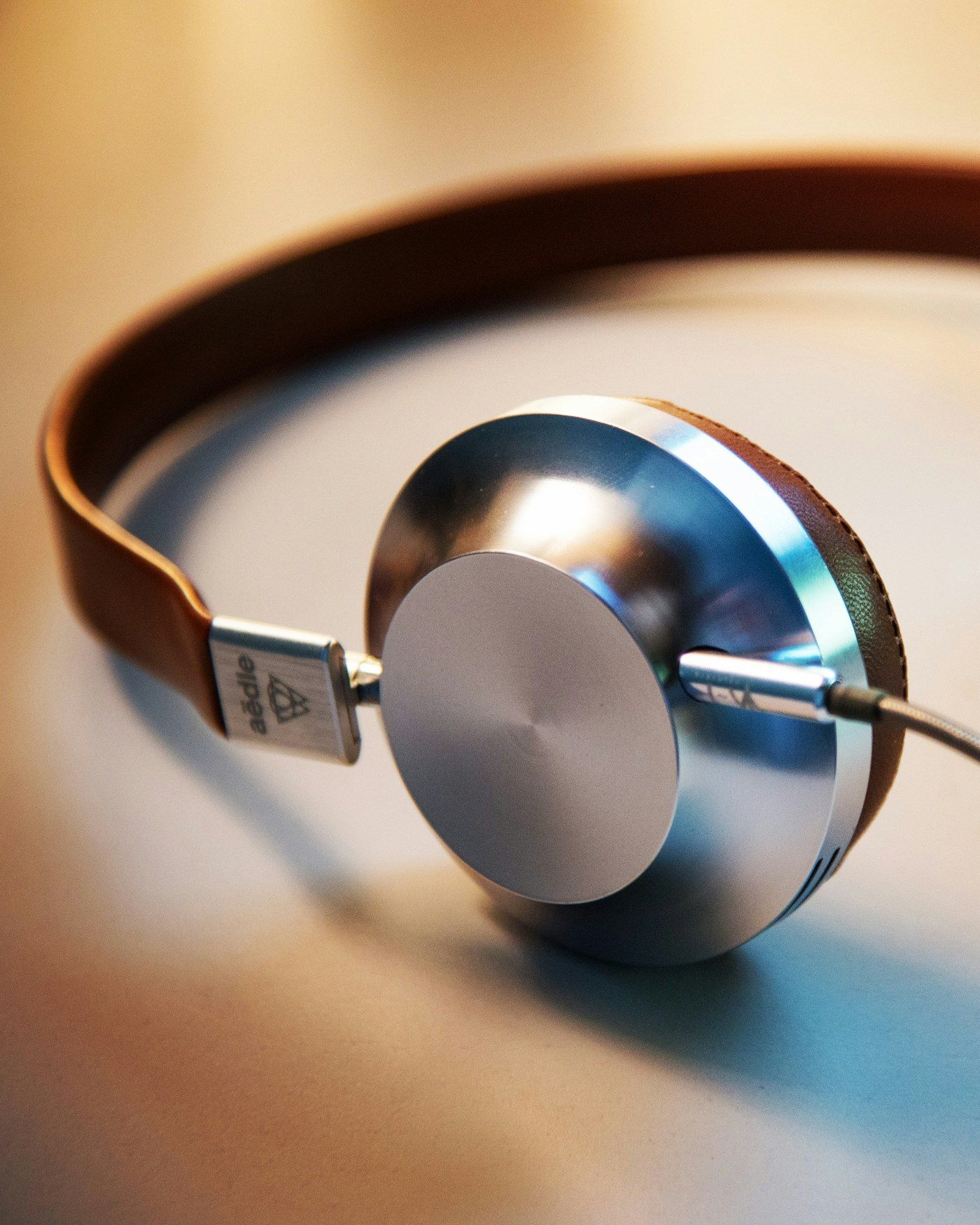 Silver and tan leather HELM headphones, warm premium finish, photographed close