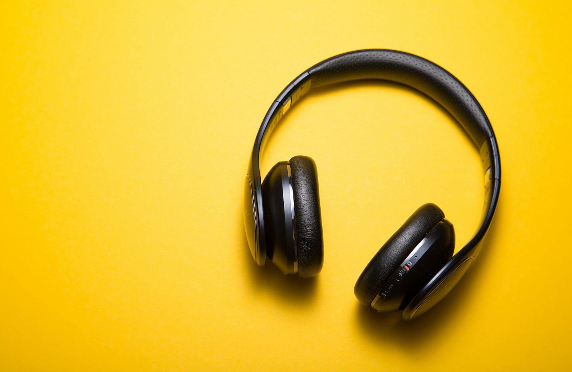Black HELM headphones in a flat-lay on a bright yellow background