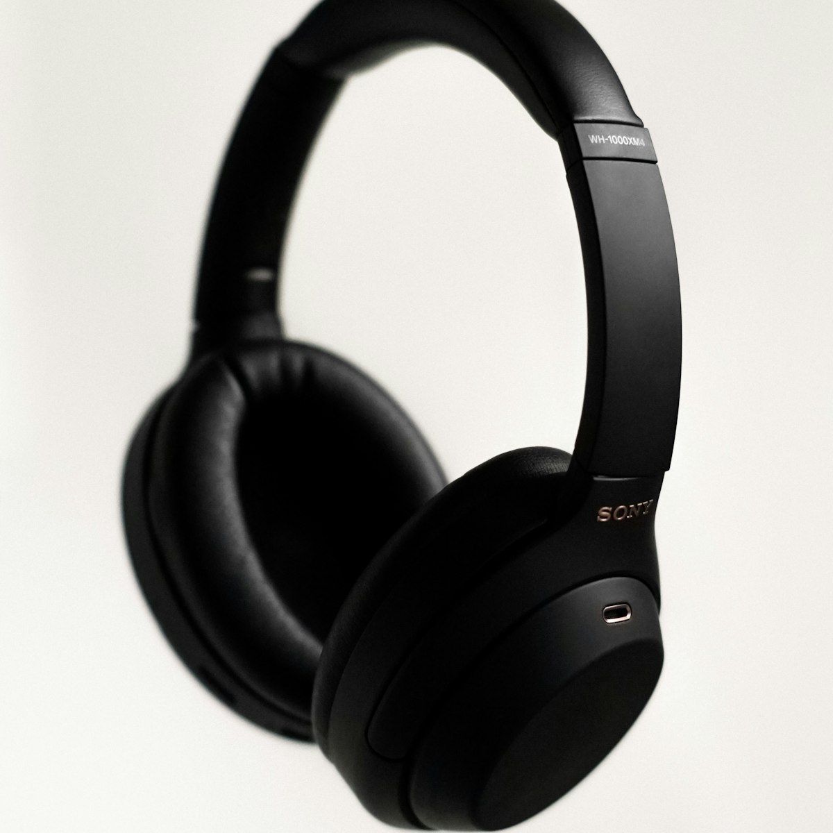 Black HELM headphones on cream backdrop, dramatic lighting