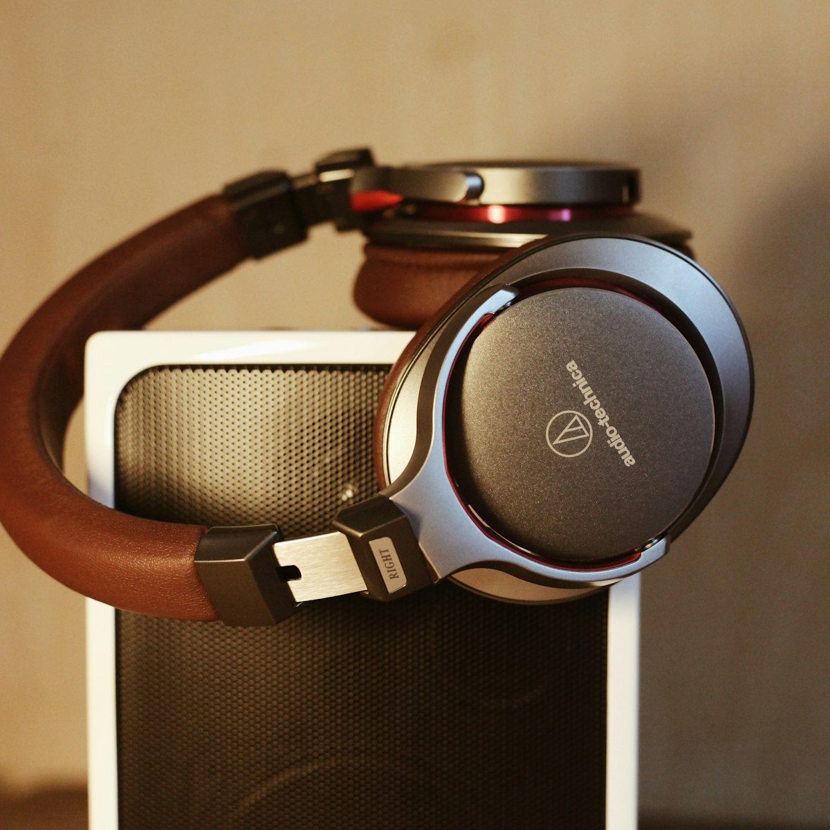 HELM headphones with silver cups and brown leather resting against a warm backdrop