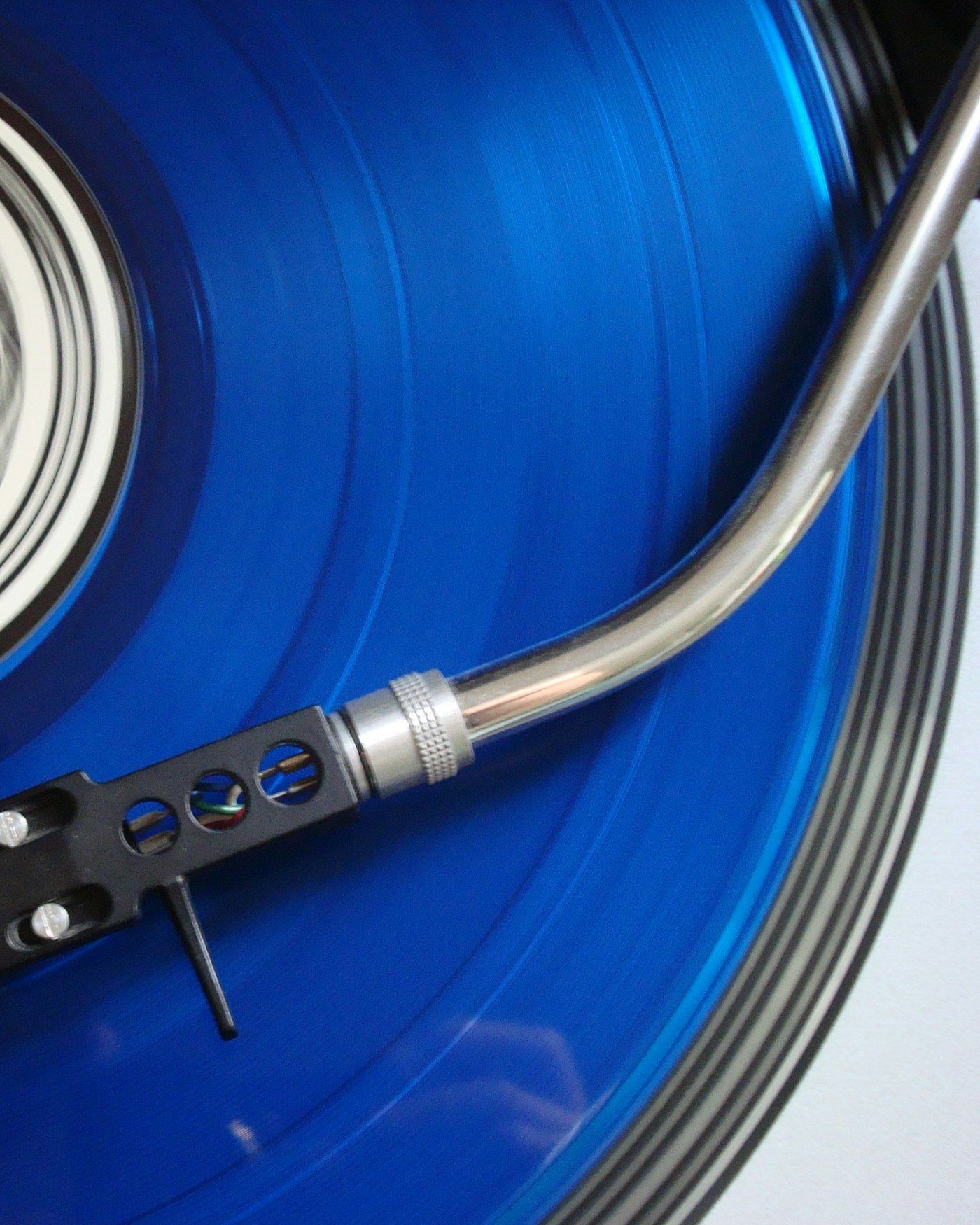Electric-blue vinyl record on a turntable with a tonearm, lit dramatically against darkness